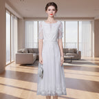Woman wearing a white lace dress against a gray background