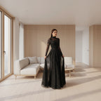 Woman wearing a black sequin dress with sheer sleeves in an indoor setting.