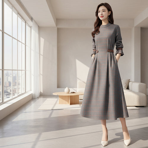 Woman wearing a gray plaid dress with brown belt in a room.