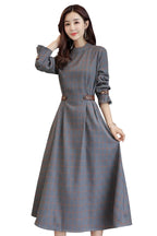 Woman wearing a gray checkered dress with a handbag on a light background