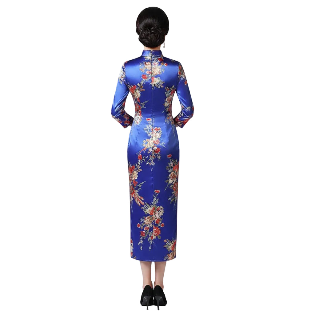 Woman in a traditional floral dress standing in a room with wooden furniture and decor.
