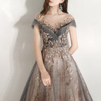 Woman wearing a gray evening gown with floral embellishments on a white background