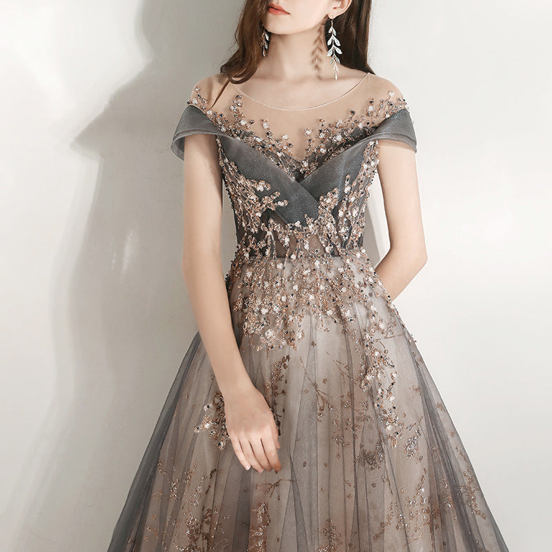 Woman wearing a gray evening gown with floral embellishments on a white background